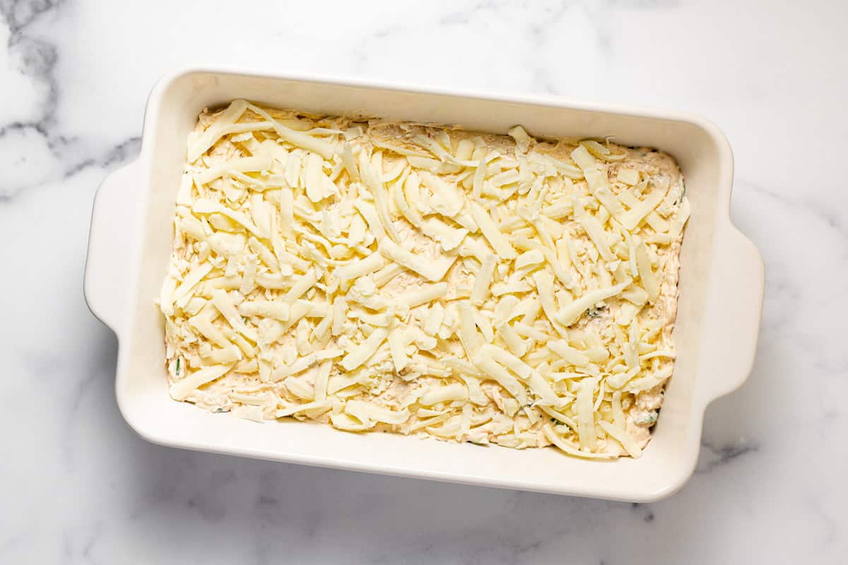 White baking dish filled with creamy crab dip that is ready to go in the oven