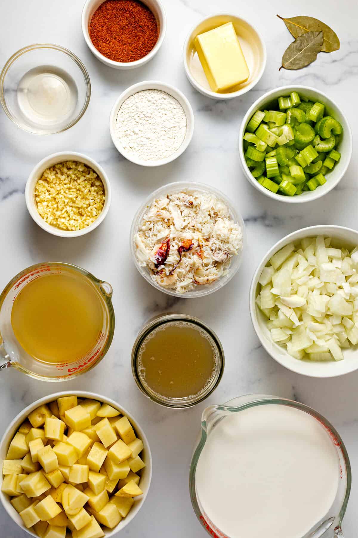 White marble counter top with bowls of ingredients to make creamy crab chowder