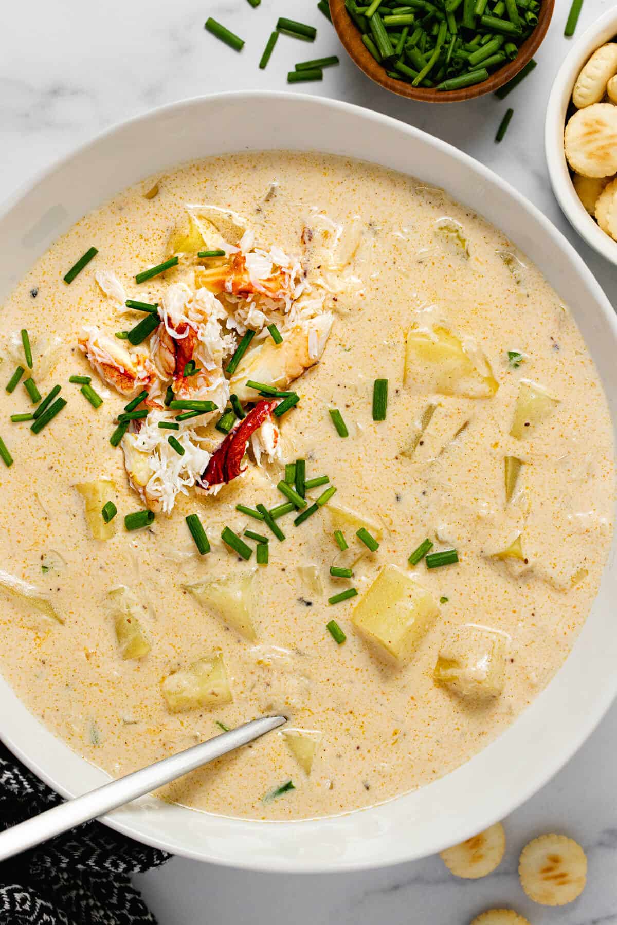 White bowl filled with homemade creamy crab chowder garnished with chives