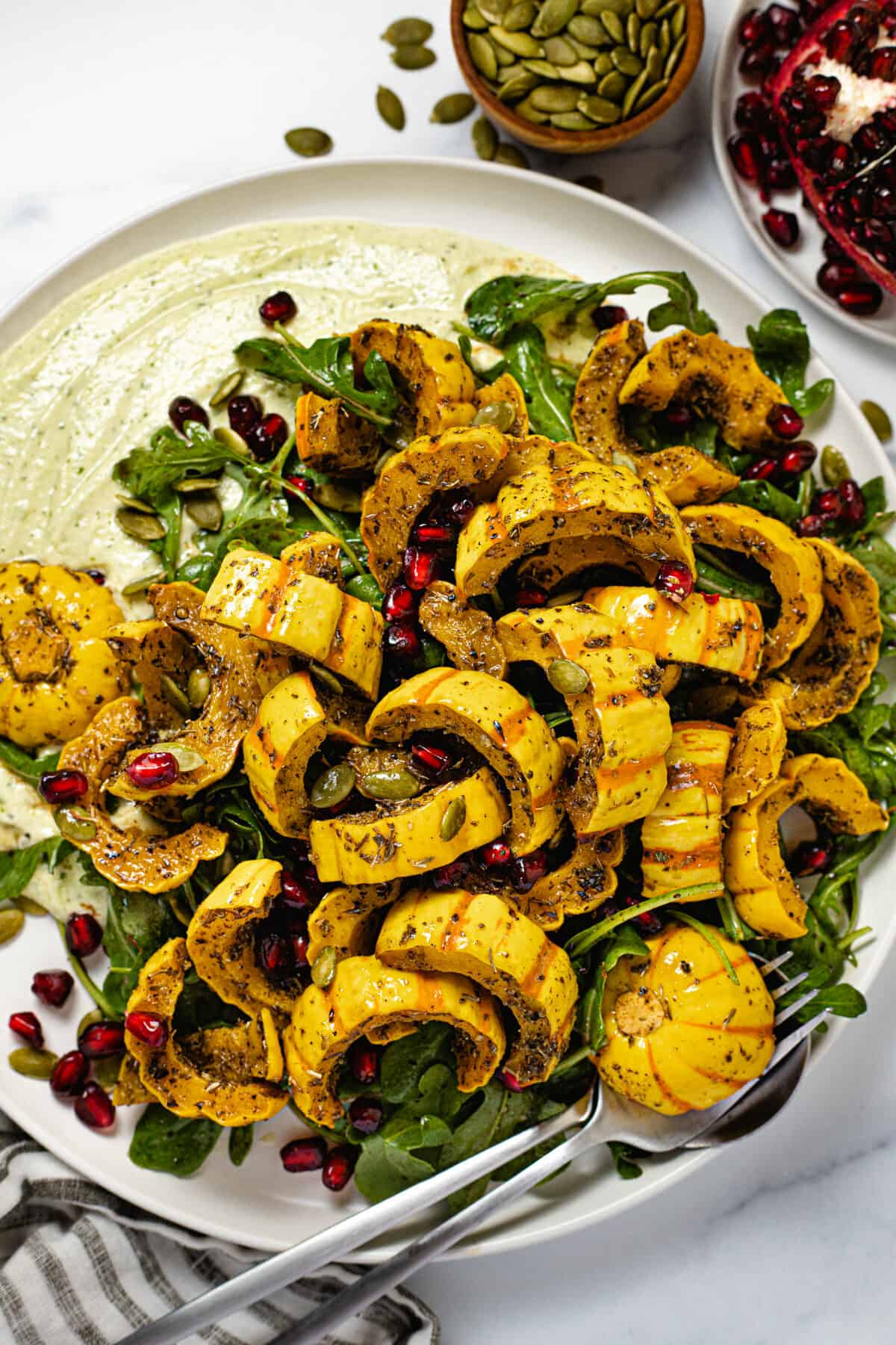 Large white plate filled with fresh green and roasted delicata squash