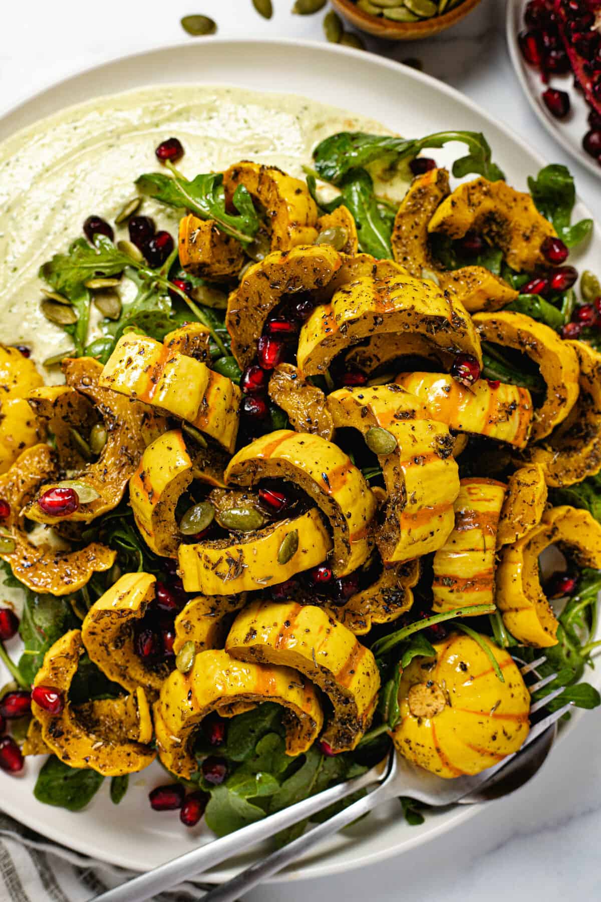 Large white plate filled with fresh green and roasted delicata squash