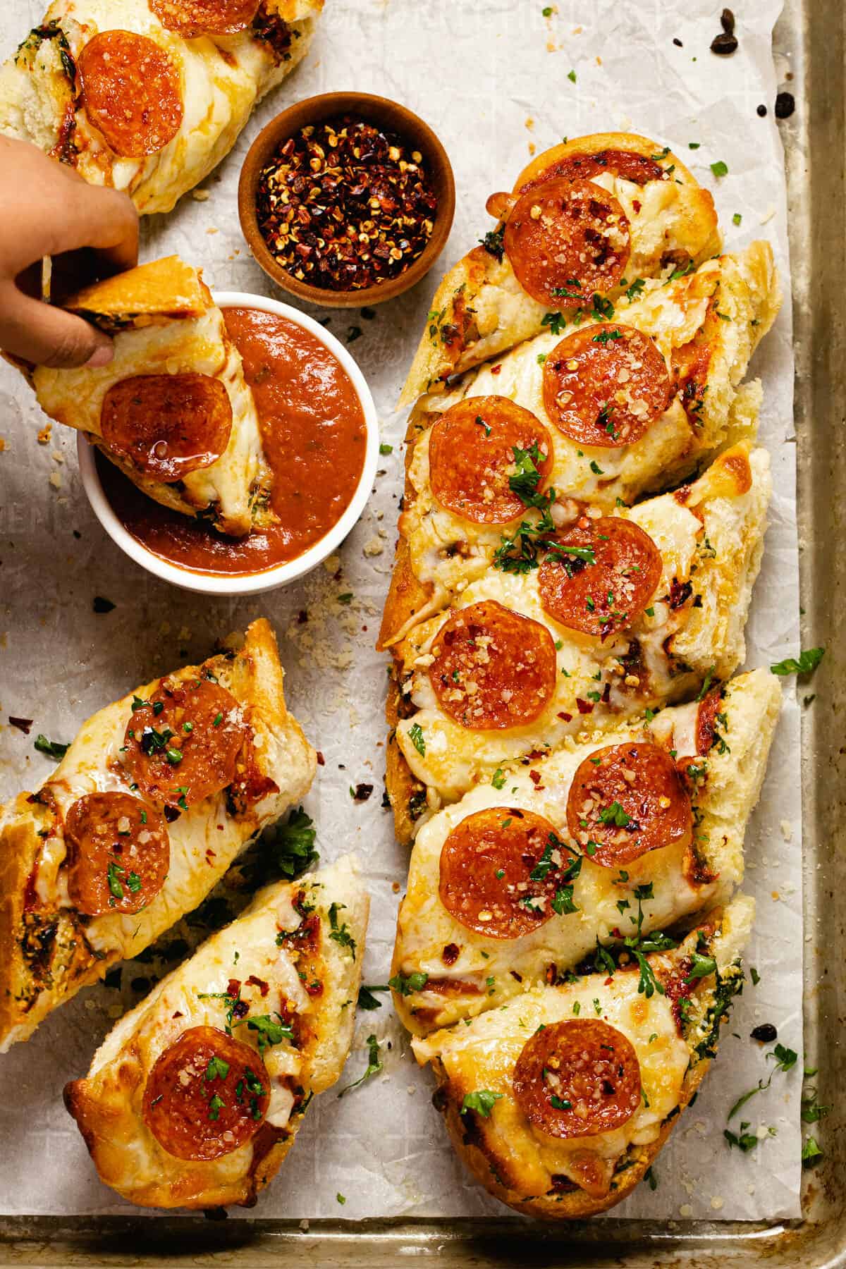 Baking sheet with homemade garlic bread pizza and a small bowl of pizza sauce