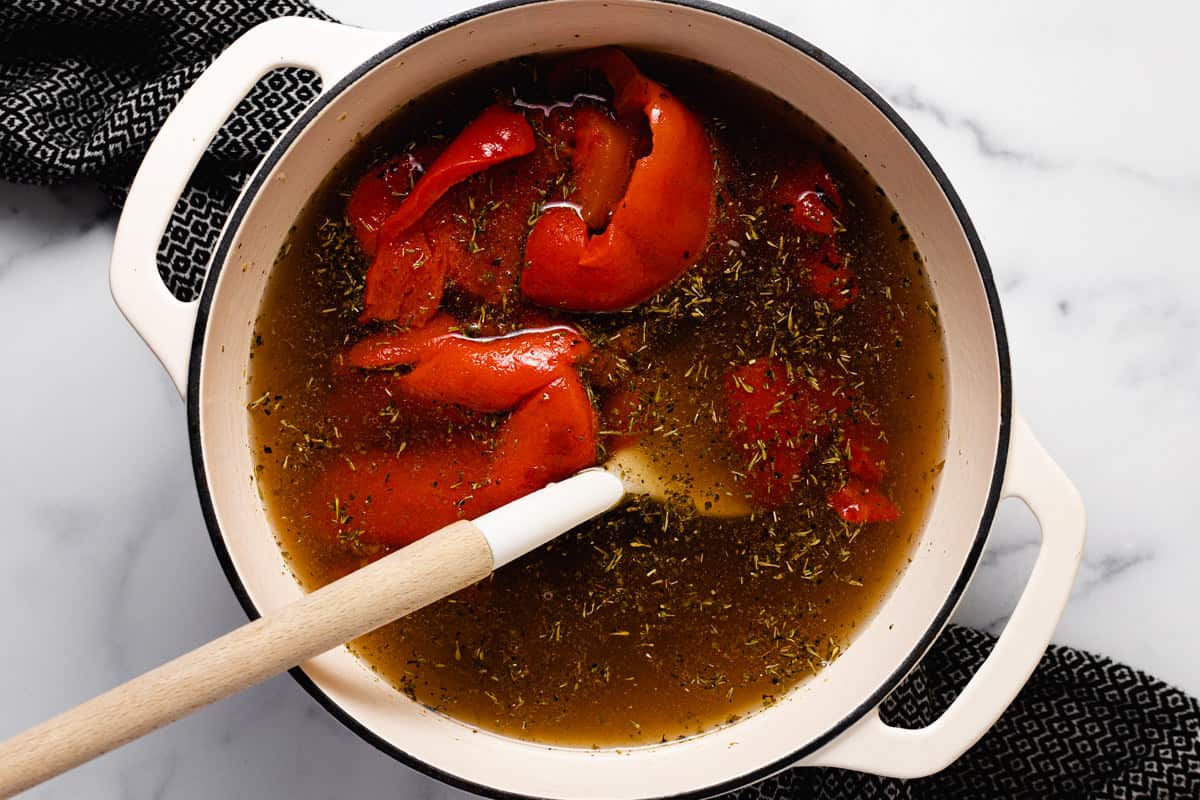 Large white pot filled with ingredients to make roasted red pepper soup