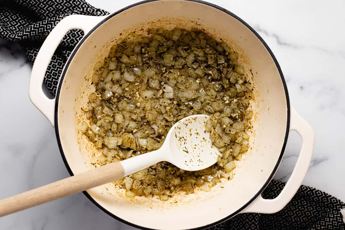 Large white pot filled with sautéed onion garlic and herbs
