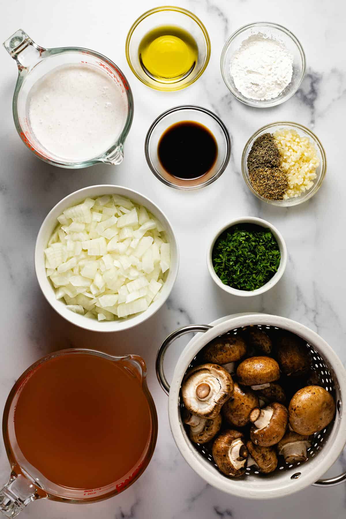 White marble counter top with ingredients to make creamy vegan mushroom soup