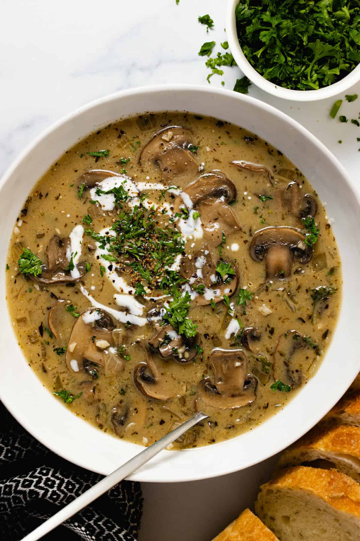 White bowl filled with creamy vegan mushroom soup garnished with parsley
