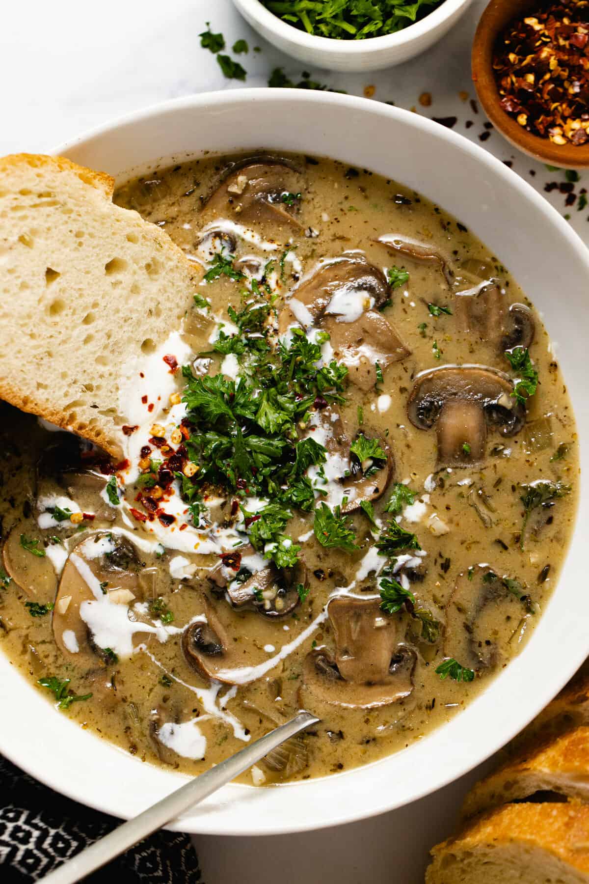 Overhead shot of a white bowl filled with vegan mushroom soup garnished with parsley