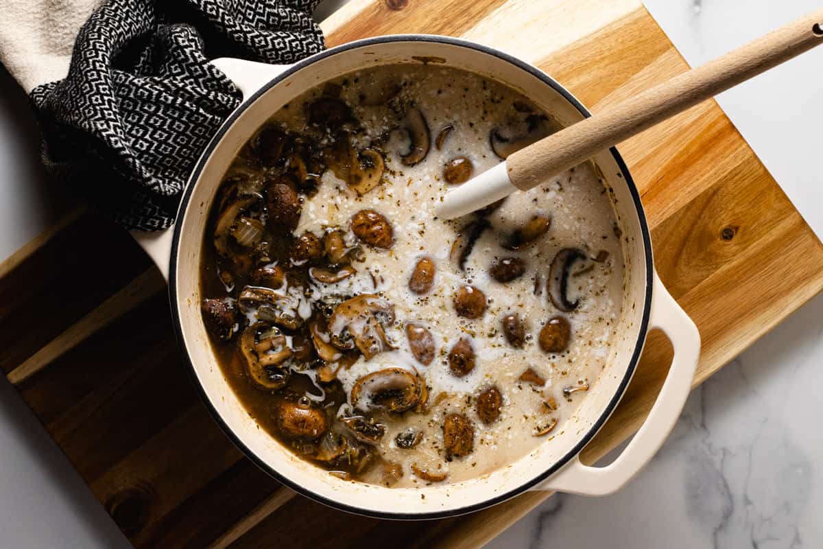 White pot filled with ingredients to make creamy vegan mushroom soup