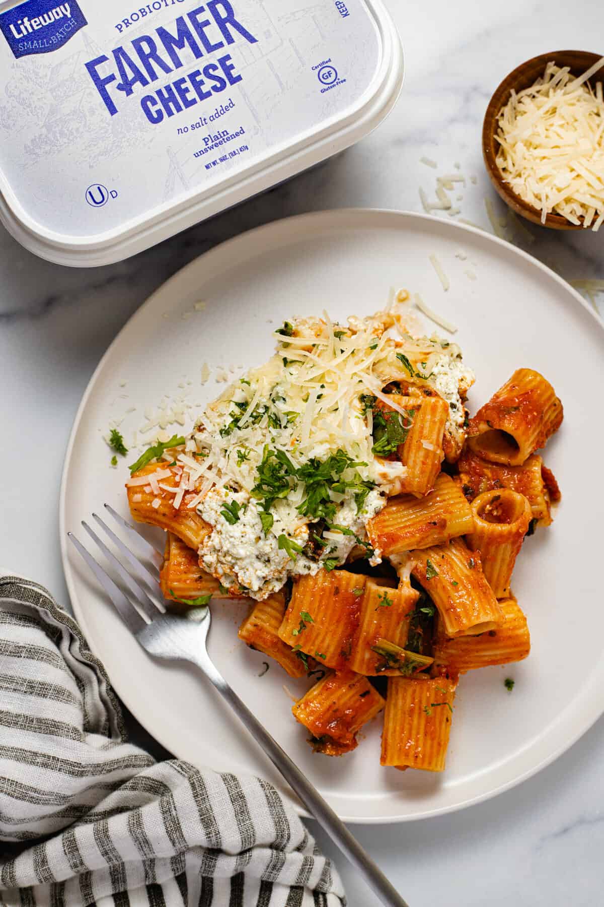 Large white plate filled with baked rigatoni garnished with parsley and Parmesan