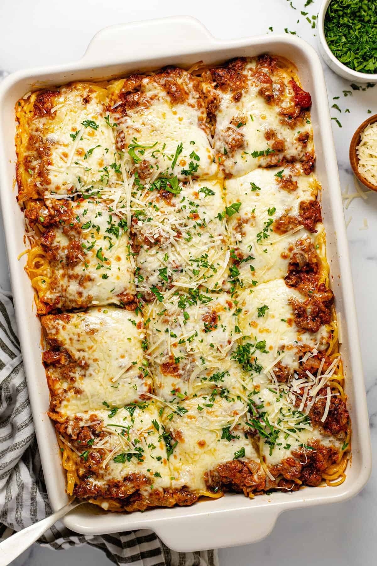 Overhead shot of a baking dish filled with baked spaghetti garnished with parsley