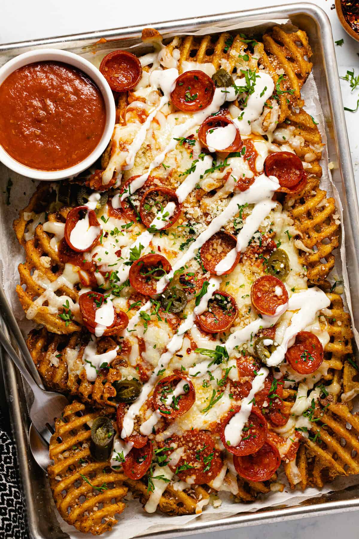 A small baking sheet filled with homemade pizza fries drizzled with ranch dressing