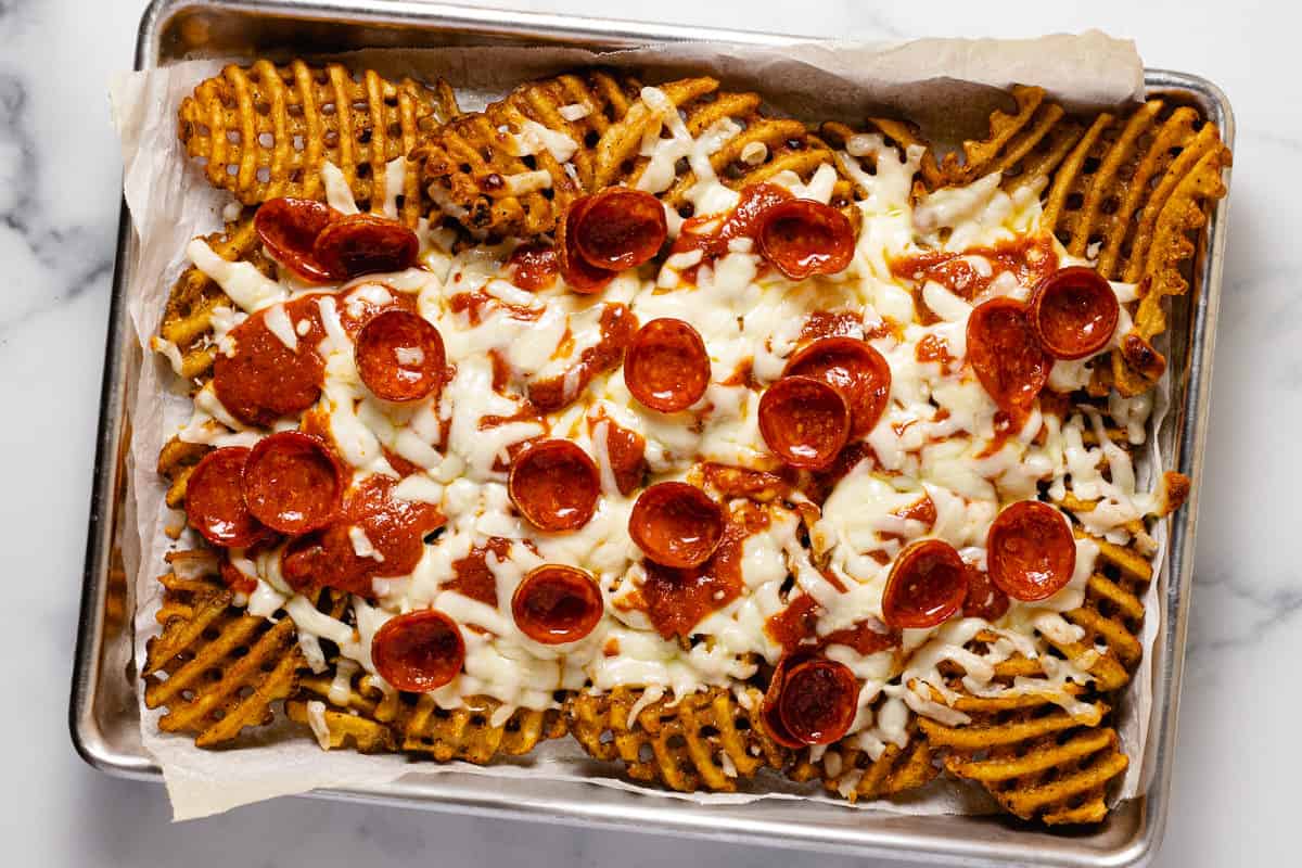Small parchment-lined baking sheet with freshly baked pizza fries