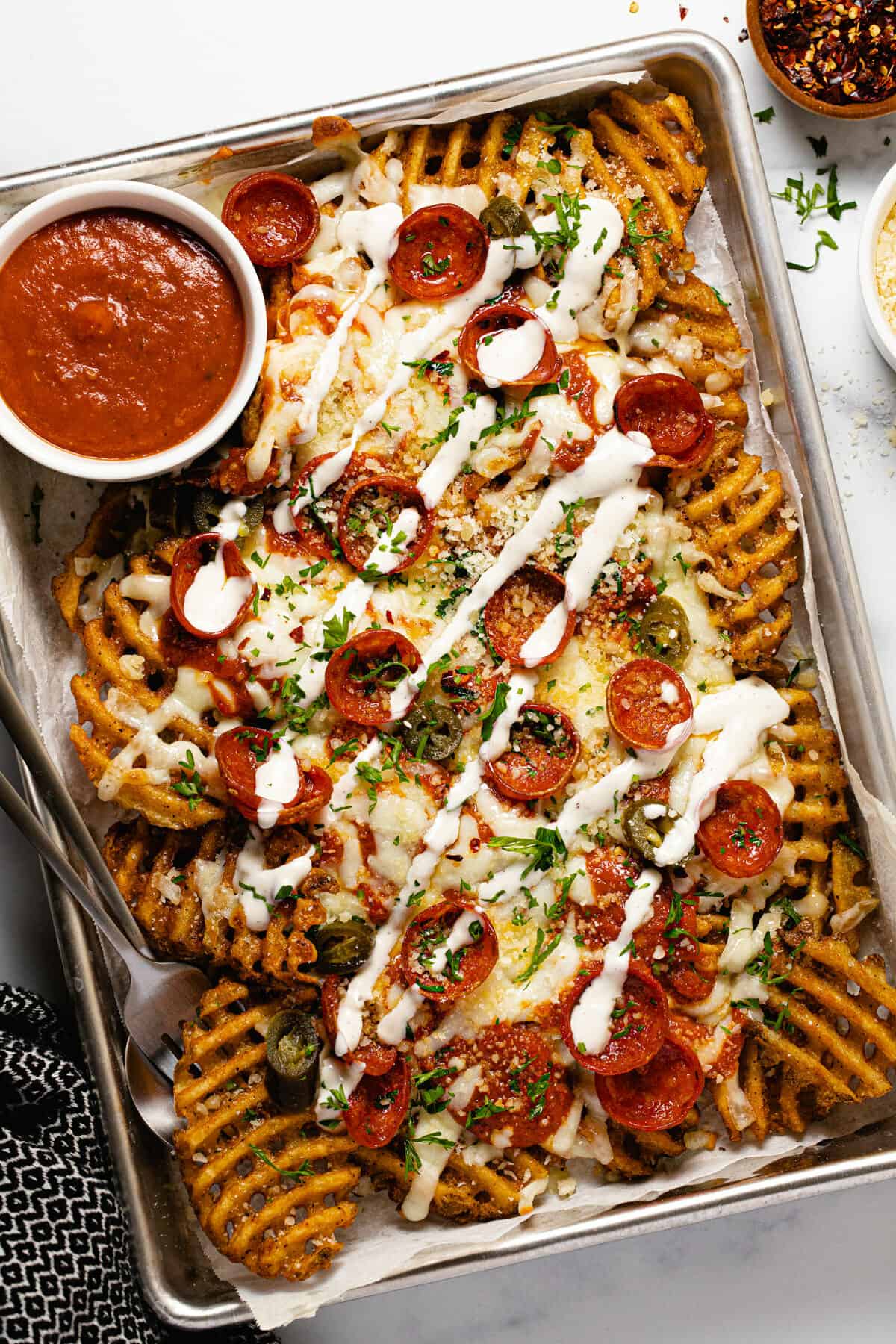 A small baking sheet filled with homemade pizza fries drizzled with ranch dressing