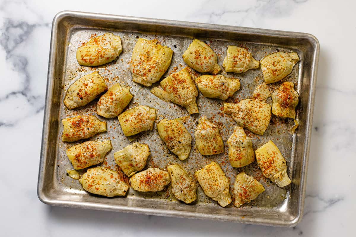 Seasoned artichoke hearts on a baking sheet