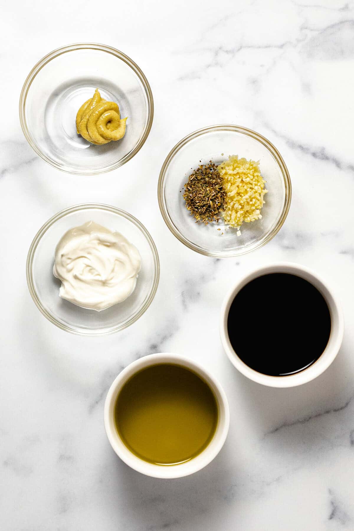 Ingredients to make balsamic dressing on a white marble counter top