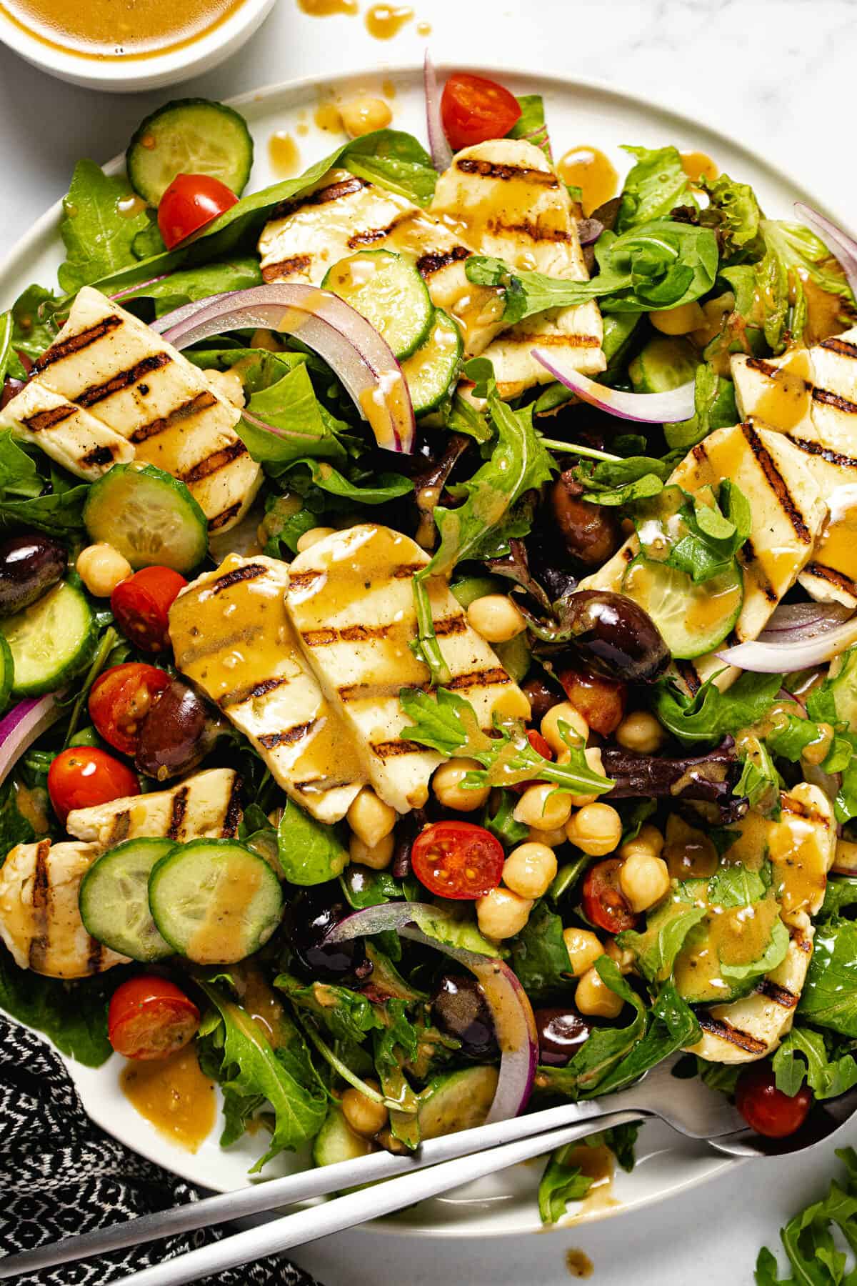 Close up shot of a halloumi salad drizzled with creamy balsamic vinaigrette dressing