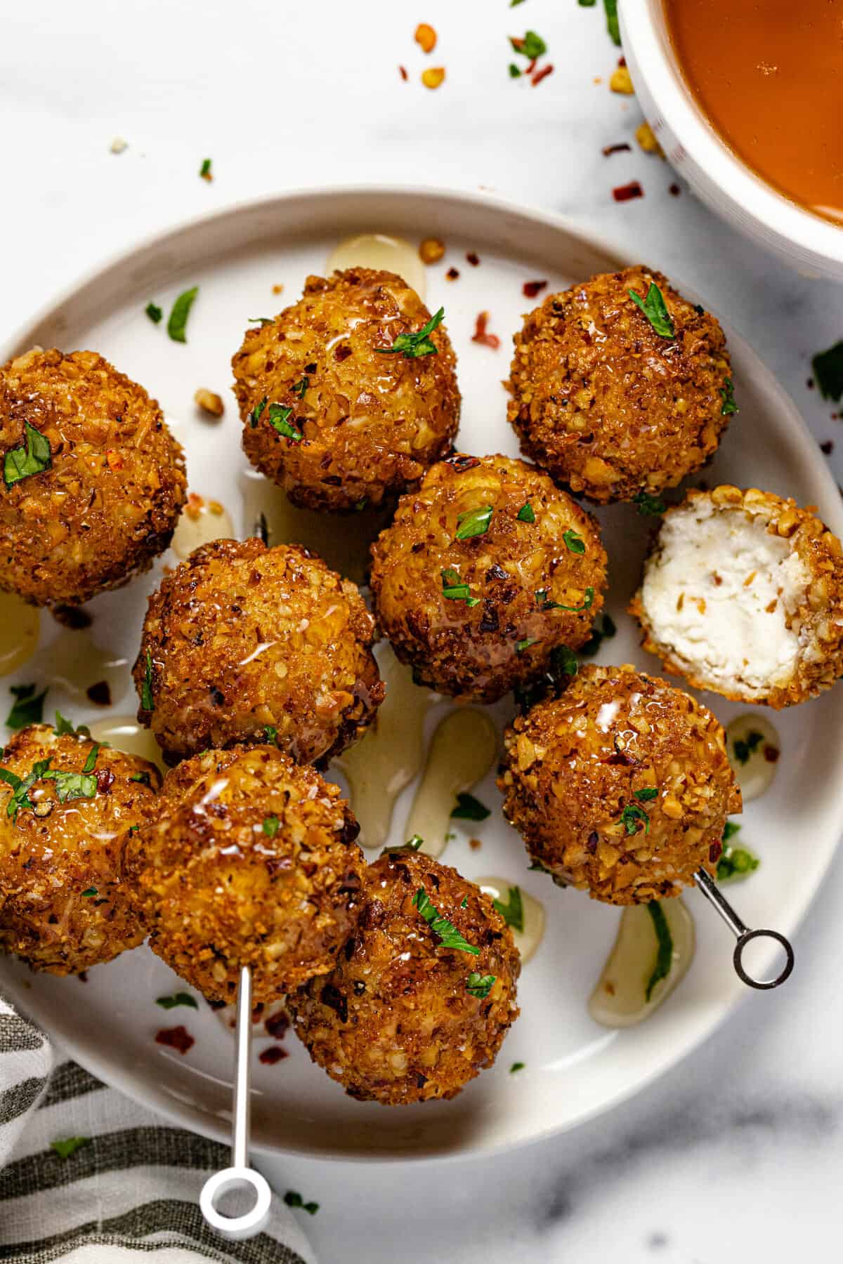 Small white plate with metal skewers speared with fried goat cheese balls