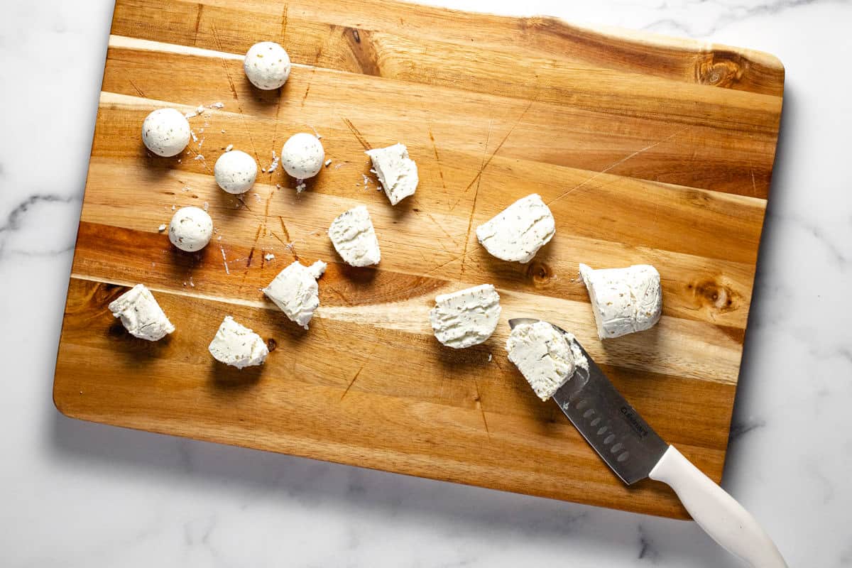 Wooden cutting board with slice goat cheese on it