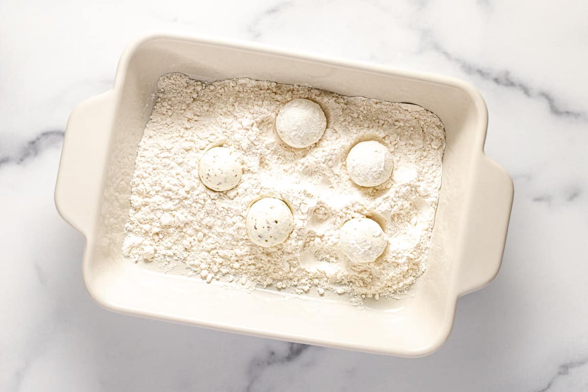 White rectangle dish with flour and round balls of goat cheese in it