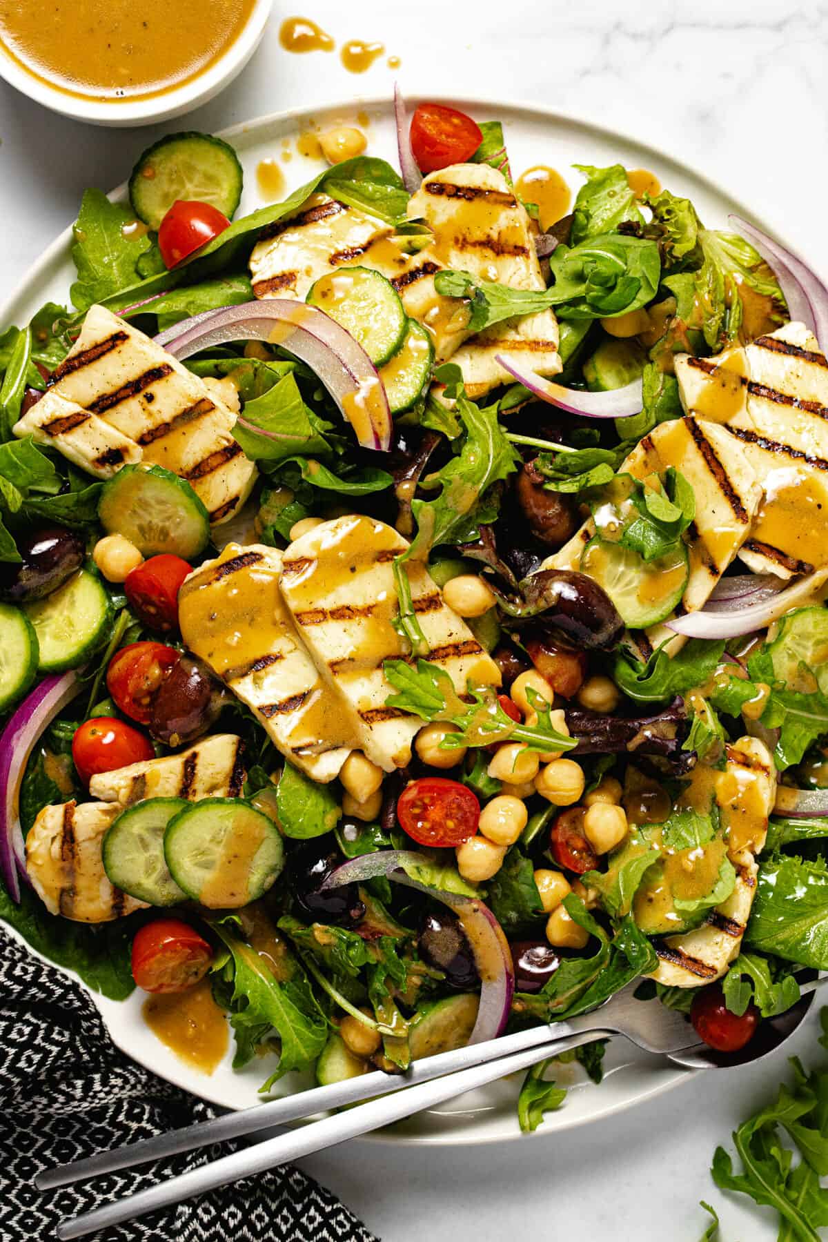 White plate filled with mixed greens and grilled halloumi cheese