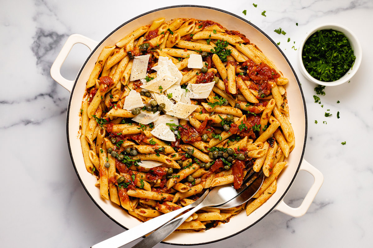 Large white pot filled with penne Pomodoro garnished with burrata and basil
