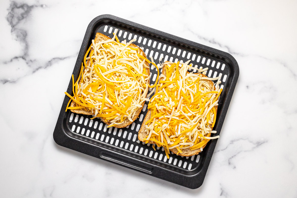Air fryer tray with two slices of bread topped with cheese