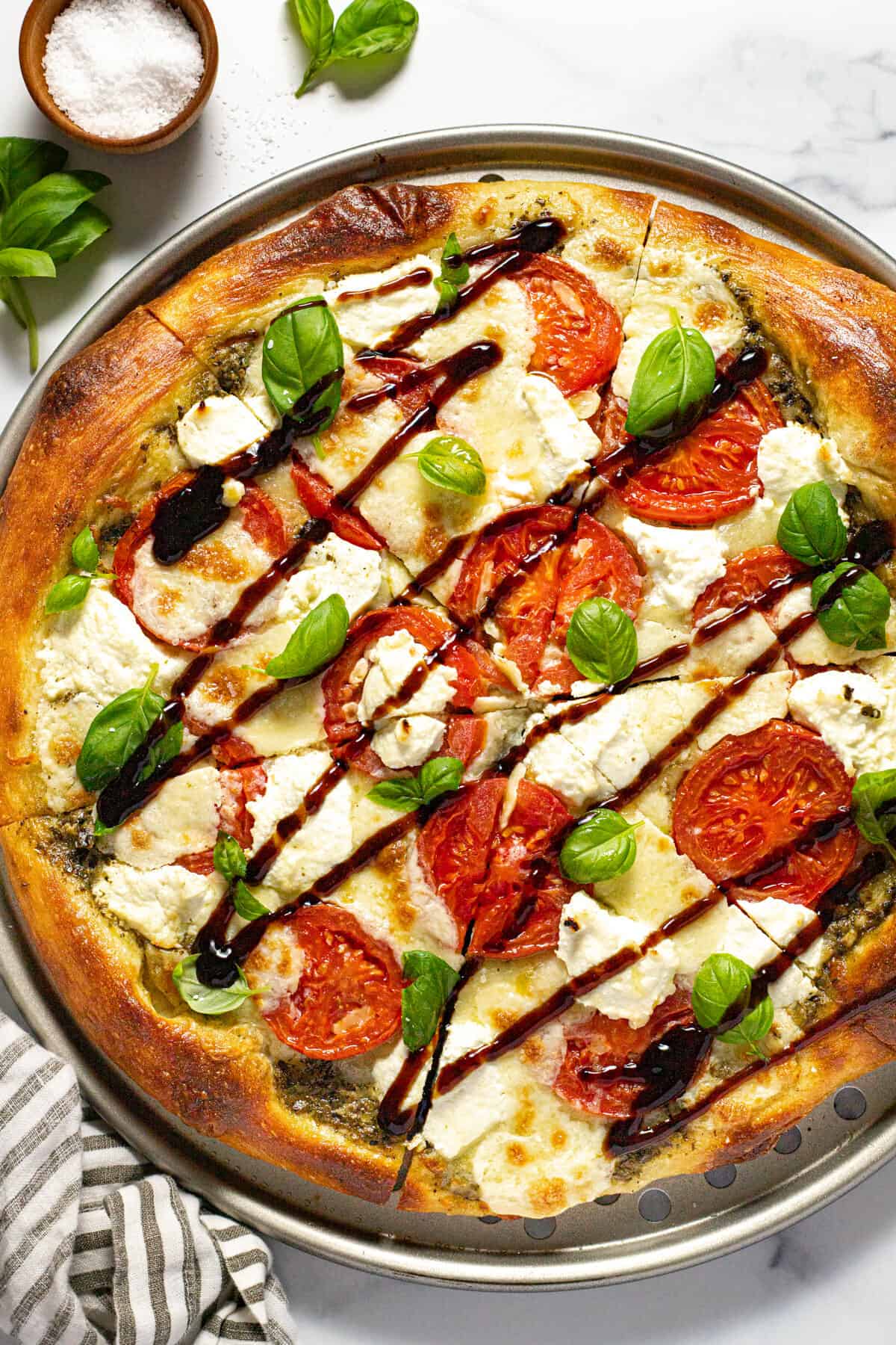 Three cheese Caprese pizza topped with basil and balsamic glaze
