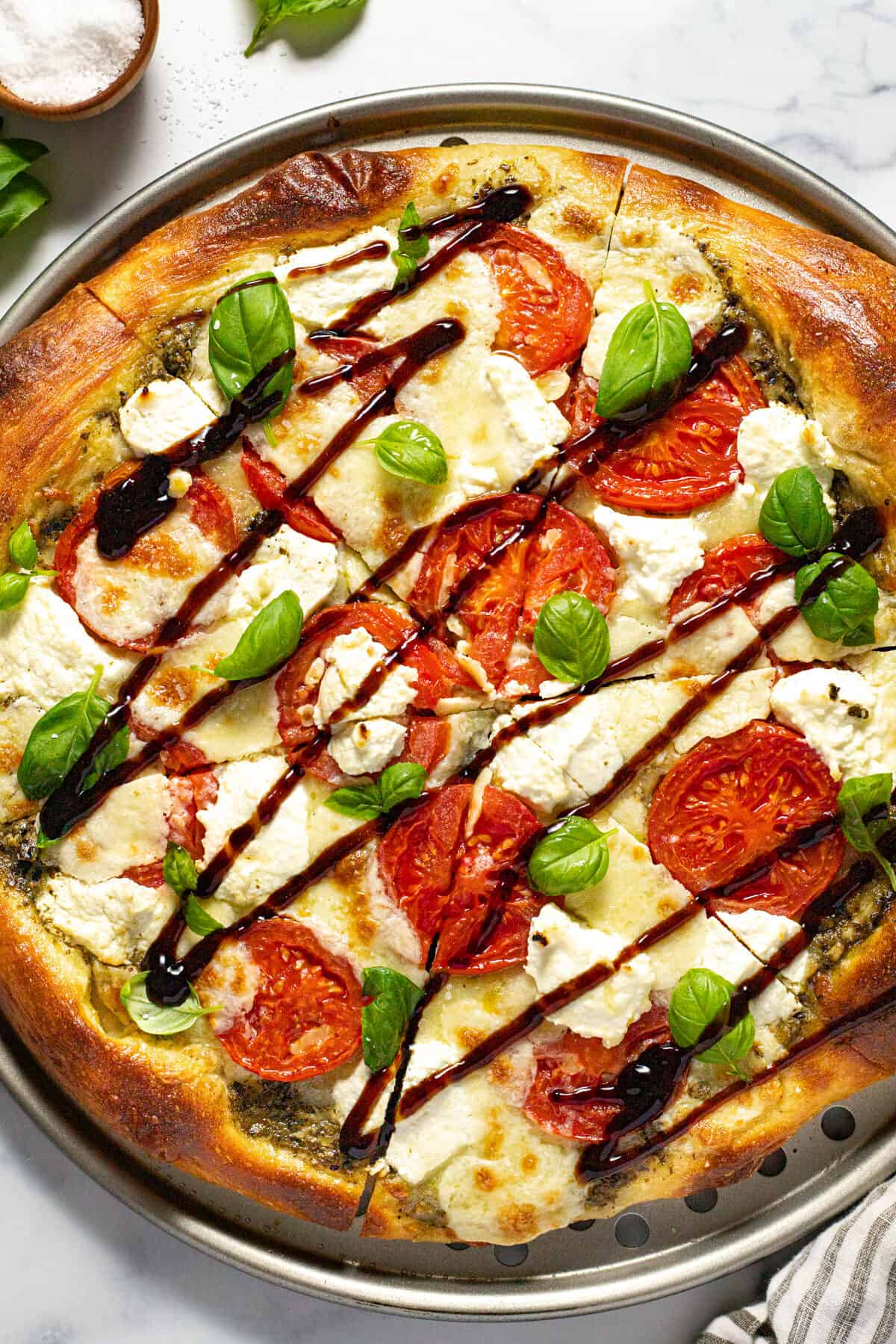 Three cheese Caprese pizza topped with basil and balsamic glaze