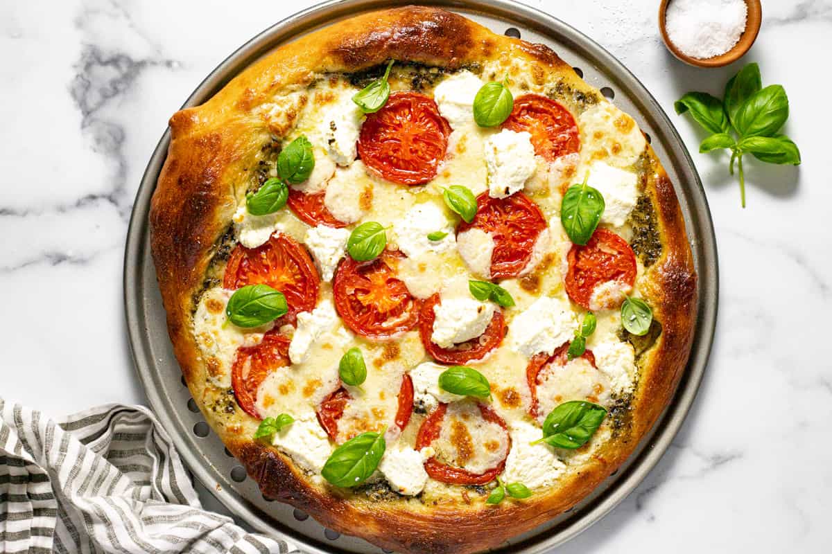 Freshly baked three cheese Caprese pizza topped with fresh basil