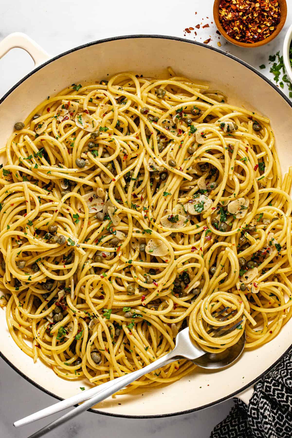 Large pan filled with olive oil pasta garnished with fresh parsley