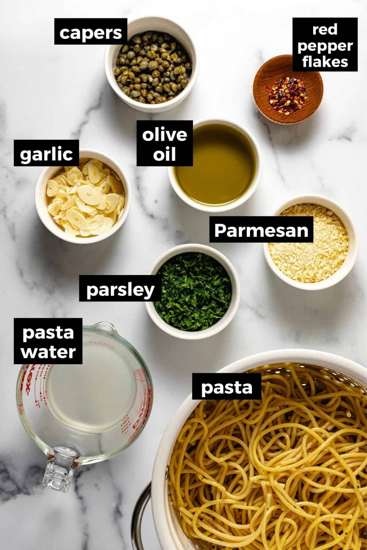 White marble countertop with bowls of ingredients to make olive oil pasta