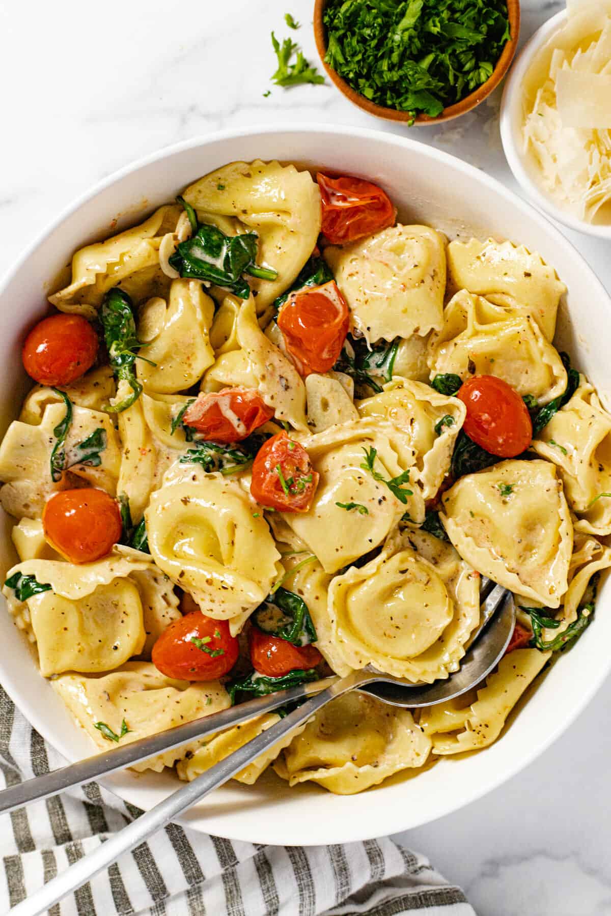 White bowl filled with cheese tortellini tossed in a garlic white wine cream sauce