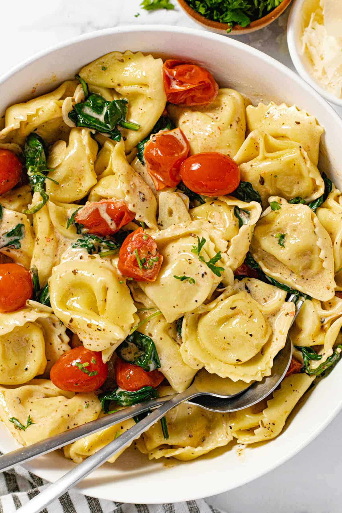 White bowl filled with cheese tortellini tossed in a garlic white wine cream sauce