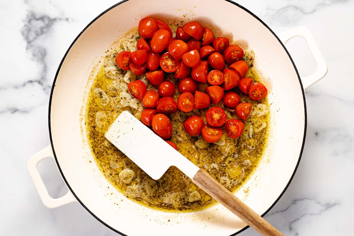 White pan filled with olive oil butter garlic and tomatoes