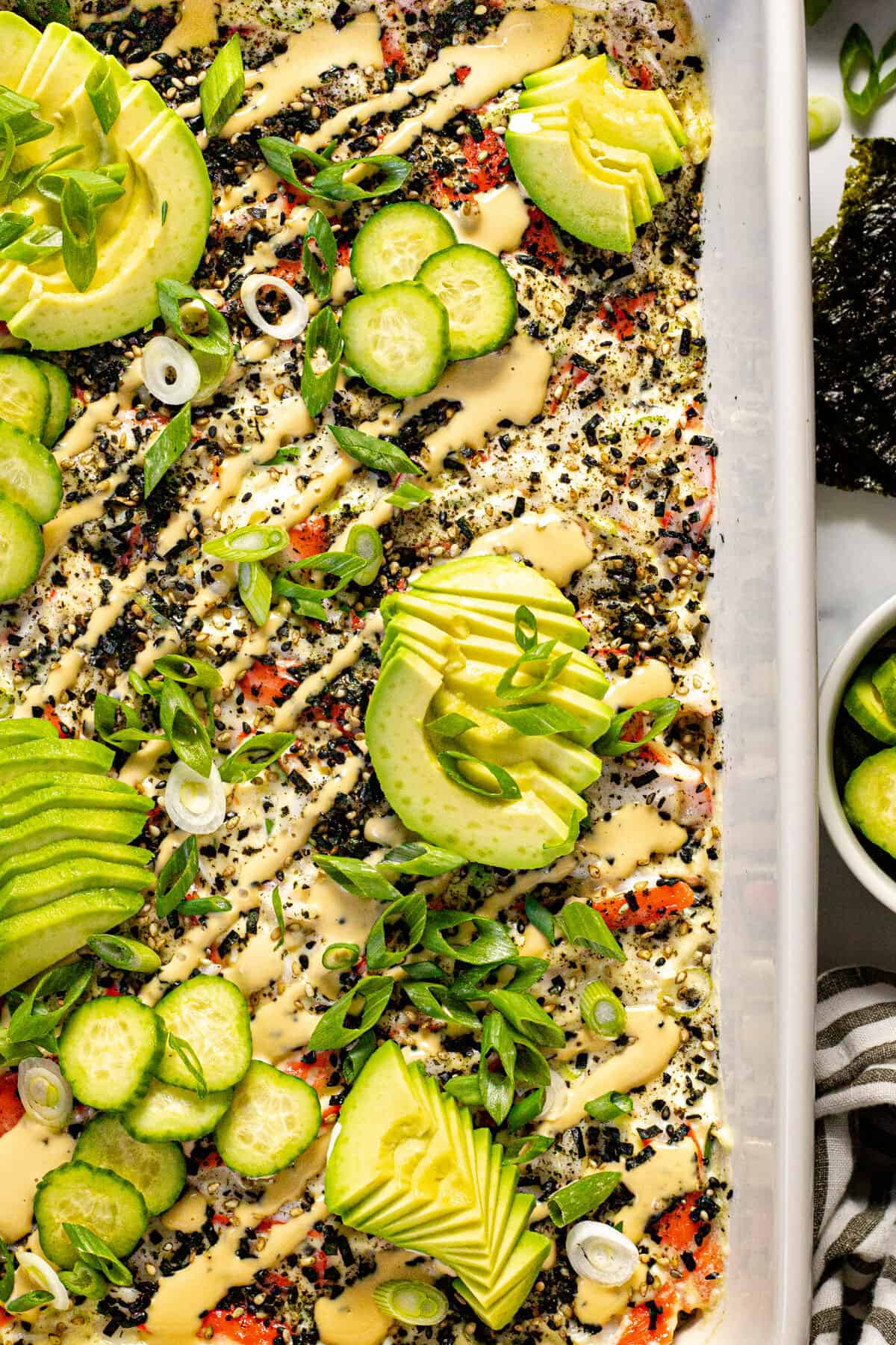 Close up shot of sushi bake topped with avocado and cucumber