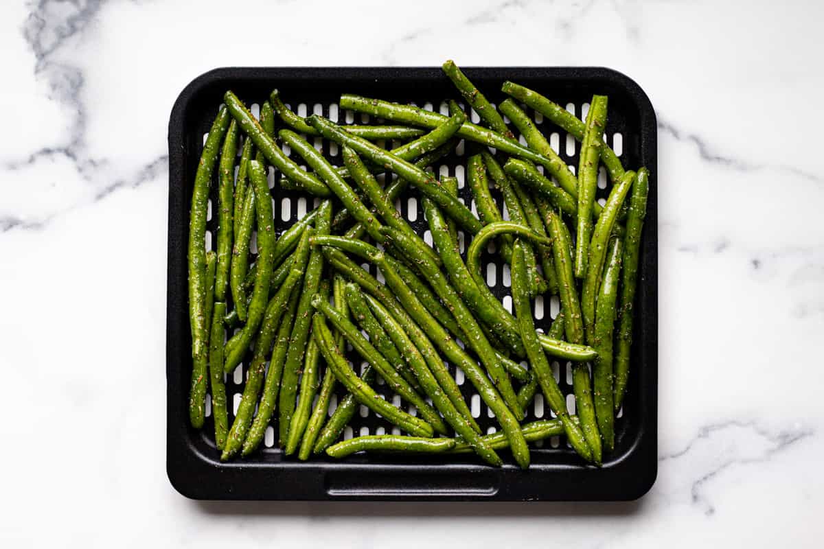 Air fryer tray with green beans ready to be cooked
