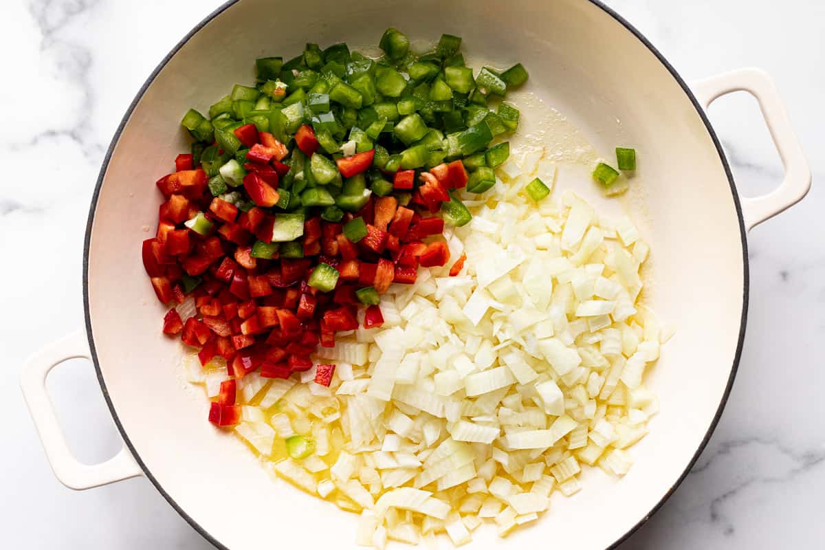 Diced veggies added to a large white pan