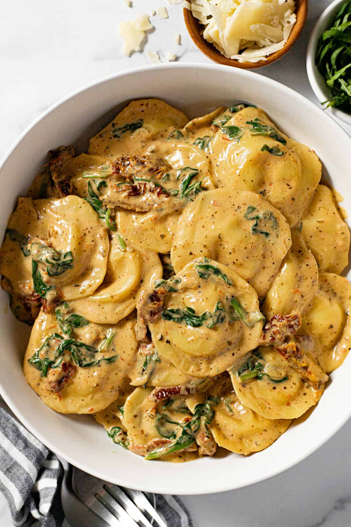 White bowl filled with cheese ravioli in sun dried tomato cream sauce