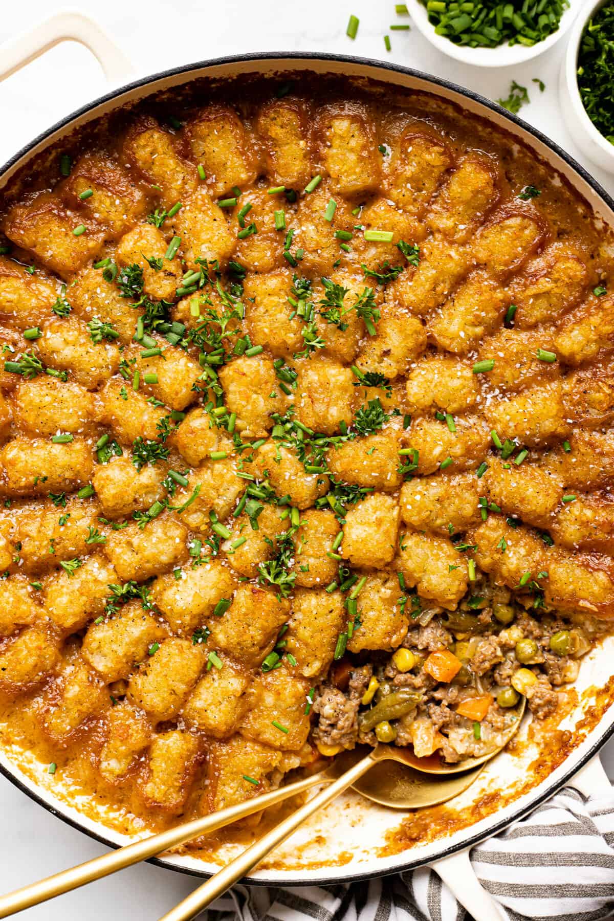 Large white pan filled with tater tot casserole garnished with chives