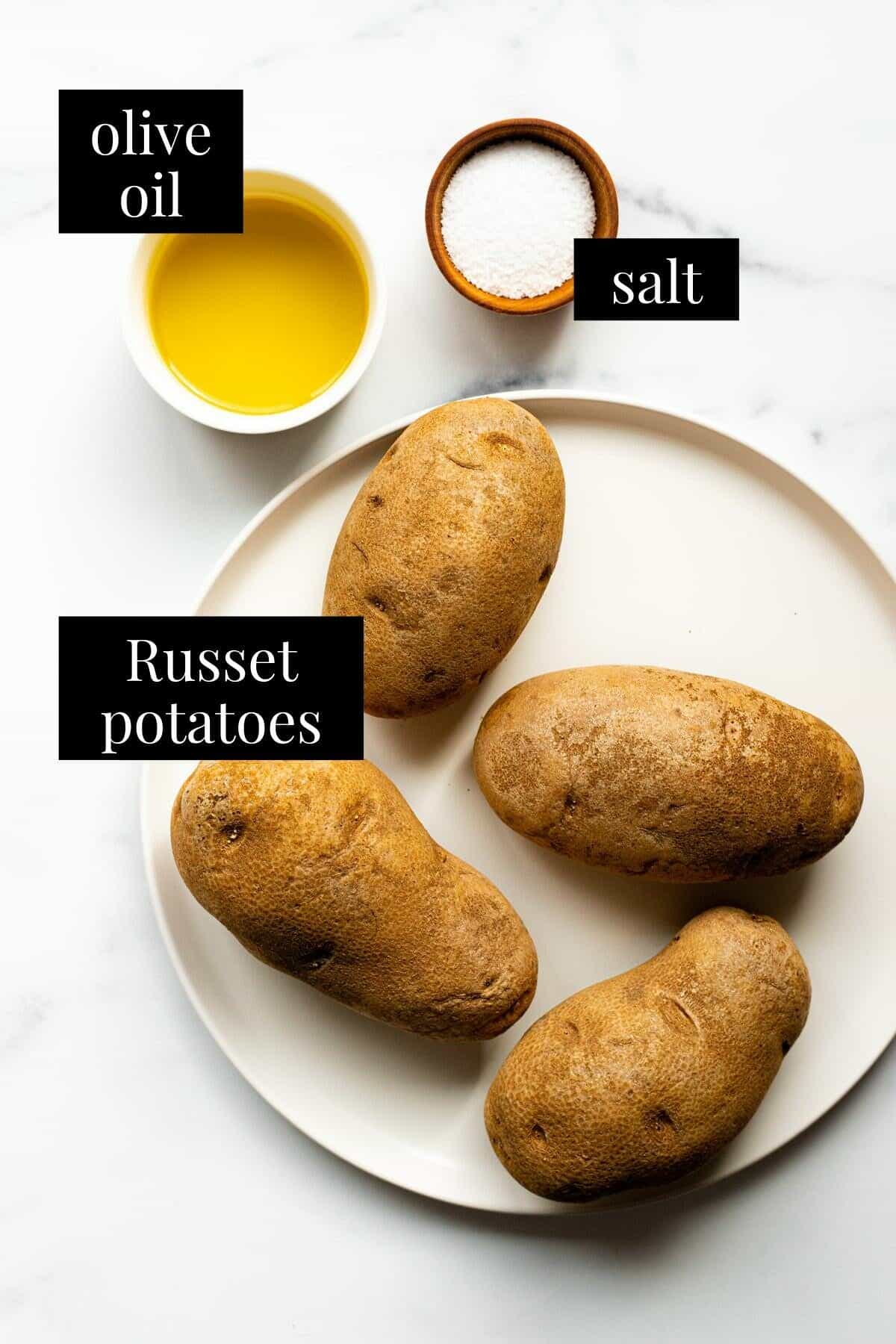 White marble counter top with ingredients to make air fryer baked potatoes