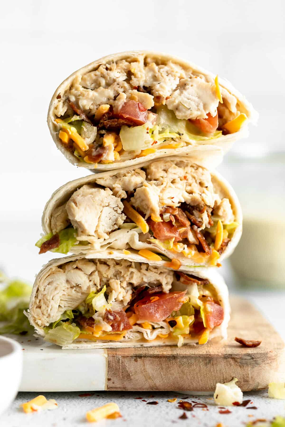A chicken bacon ranch wrap cut in half and piled on top of each other on a white plate