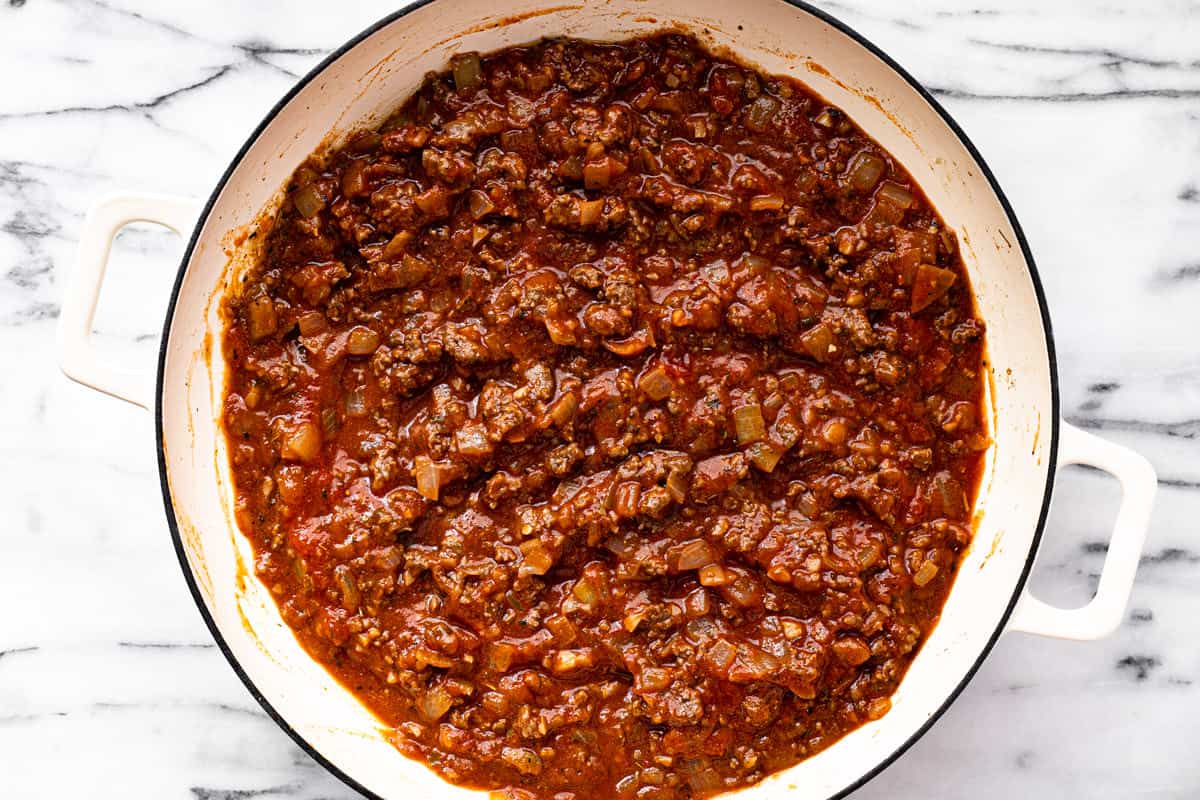 Large white pan filled with ground beef and spaghetti sauce.
