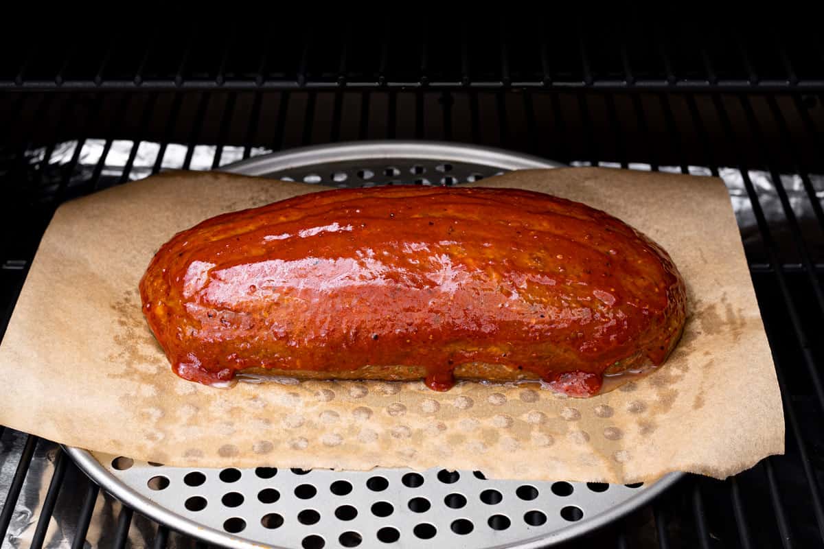 Pellet grill with homemade meatloaf topped with barbecue sauce.