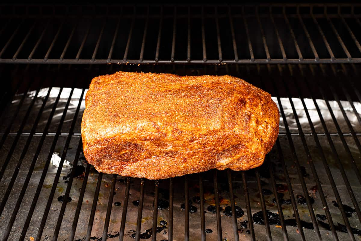 Seasoned pork butt on a grill ready to cook