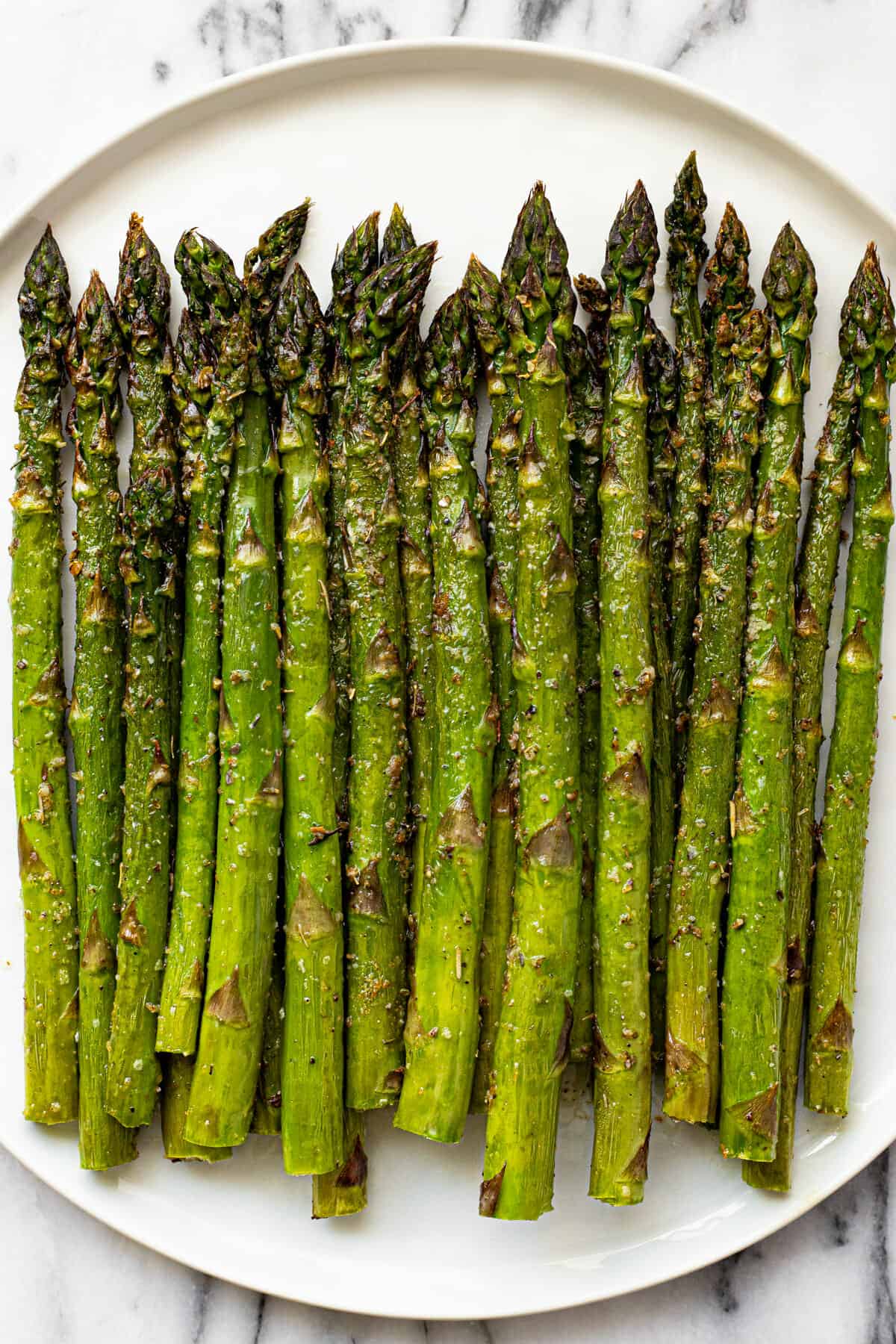 White plate filled with air fried asparagus fresh from the air fryer