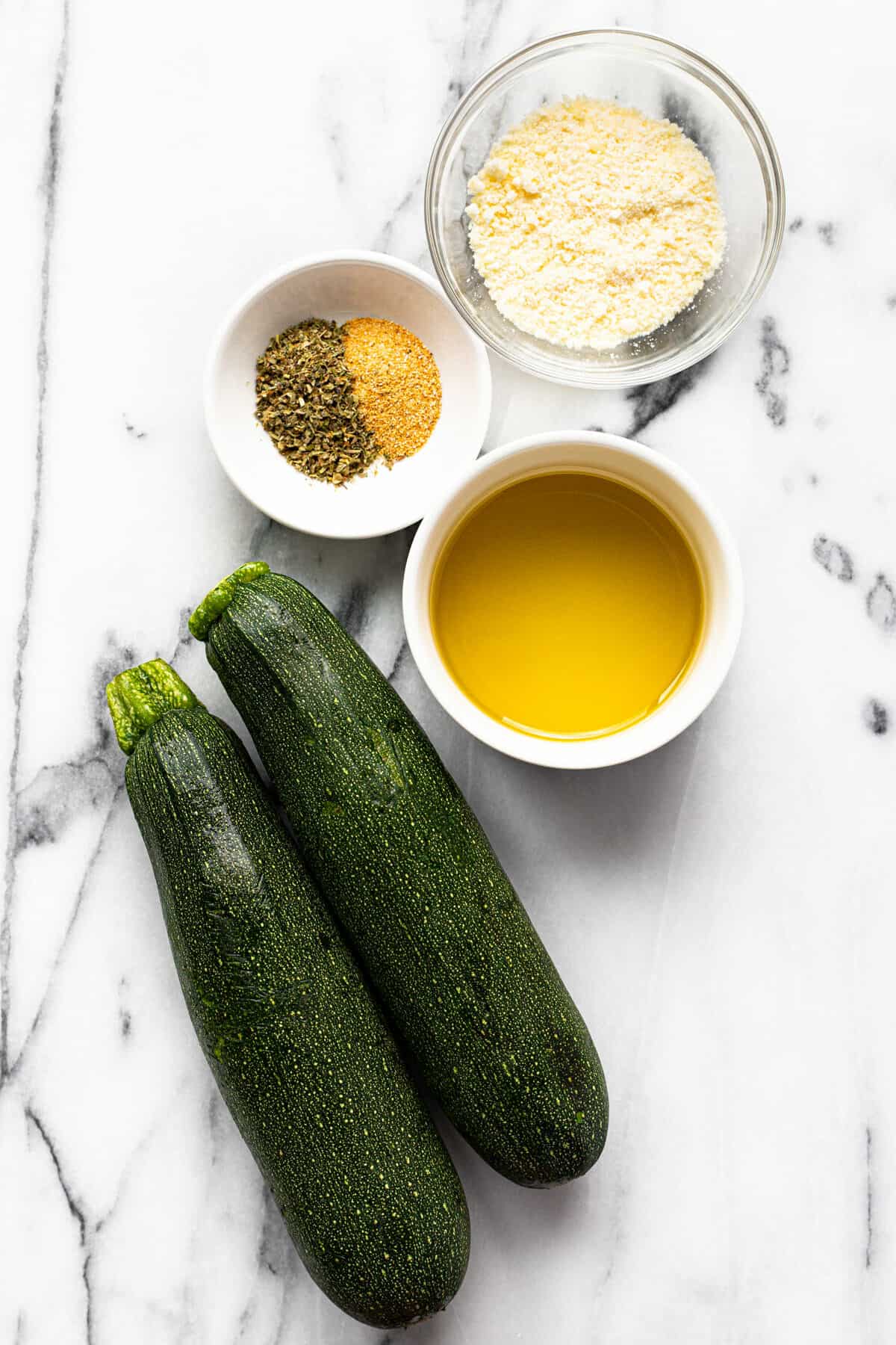 White counter top with bowls of ingredients to make air fryer zucchini.