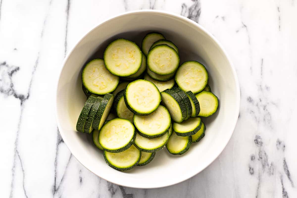 White bowl filled with sliced zucchini.