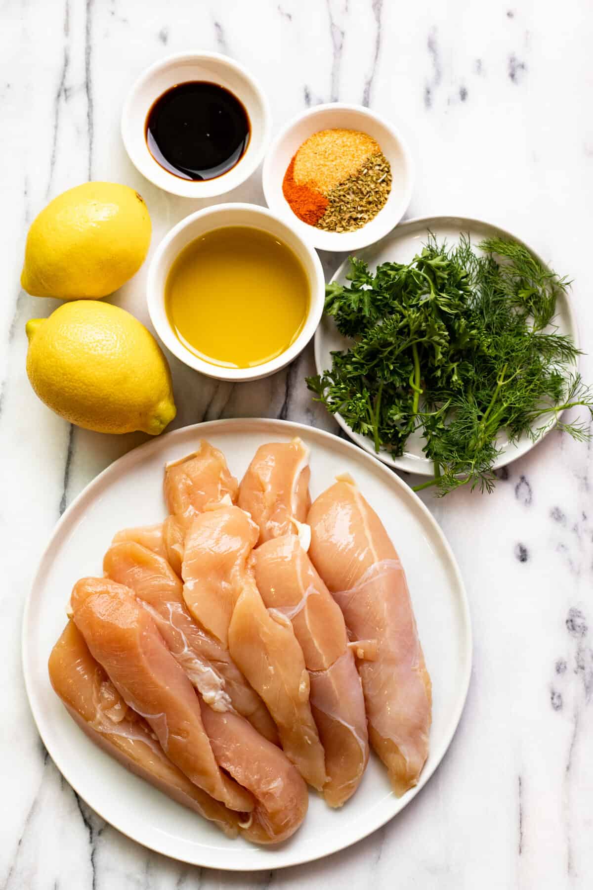 White counter top with ingredients to make a simple Greek chicken marinade.