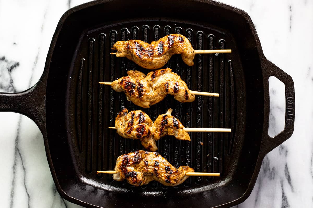 Grill pan with cooked chicken skewers in it.