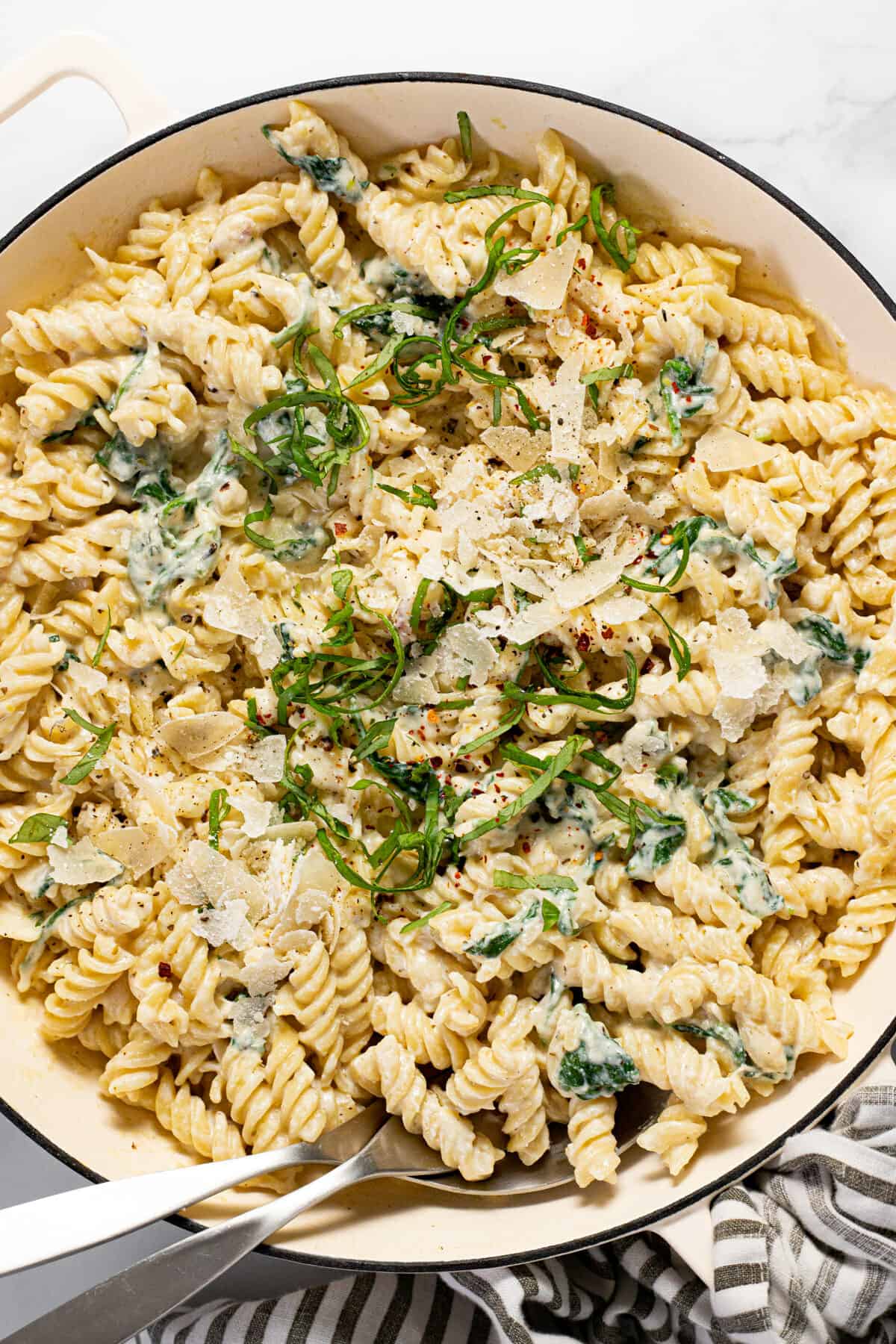 Large white pan filled with lemon ricotta pasta garnished with Parmesan cheese and fresh basil.